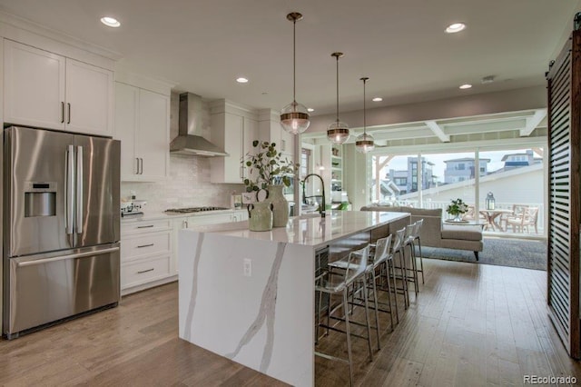5880 Beeler Ct, Denver, CO 80238 - kitchen featuring stainless steel refrigerator with ice dispenser, wall chimney exhaust hood, white cabinetry, hardwood / wood-style flooring, and gas stovetop