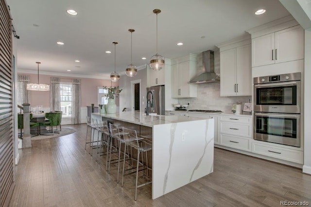 5880 Beeler Ct, Denver, CO 80238 - kitchen featuring wall chimney exhaust hood, appliances with stainless steel finishes, a spacious island, decorative backsplash, and wood finished floors