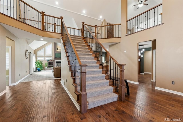 29850 E 167th Pl, Brighton, CO 80603 - staircase featuring a towering ceiling, baseboards, hardwood / wood-style flooring, ceiling fan, and a fireplace