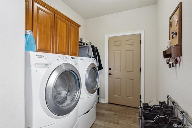 washroom with cabinets, wood-type flooring, and washer and clothes dryer