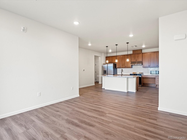 kitchen featuring sink, an island with sink, pendant lighting, appliances with stainless steel finishes, and hardwood / wood-style flooring