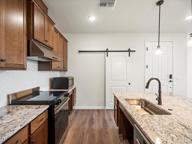 kitchen featuring sink, a barn door, dark hardwood / wood-style floors, decorative light fixtures, and appliances with stainless steel finishes