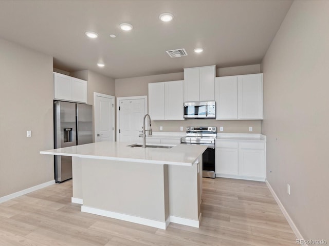 kitchen featuring white cabinetry, sink, light hardwood / wood-style flooring, an island with sink, and appliances with stainless steel finishes