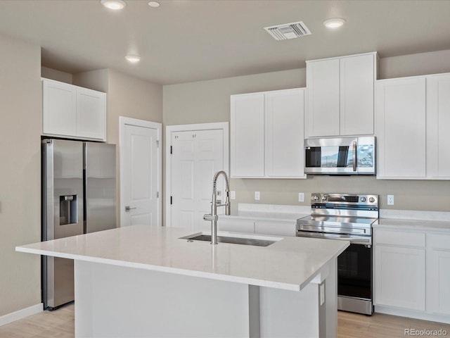 kitchen featuring sink, light hardwood / wood-style flooring, an island with sink, white cabinetry, and stainless steel appliances