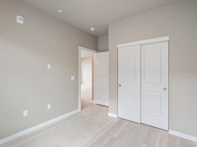 unfurnished bedroom featuring light wood-type flooring and a closet