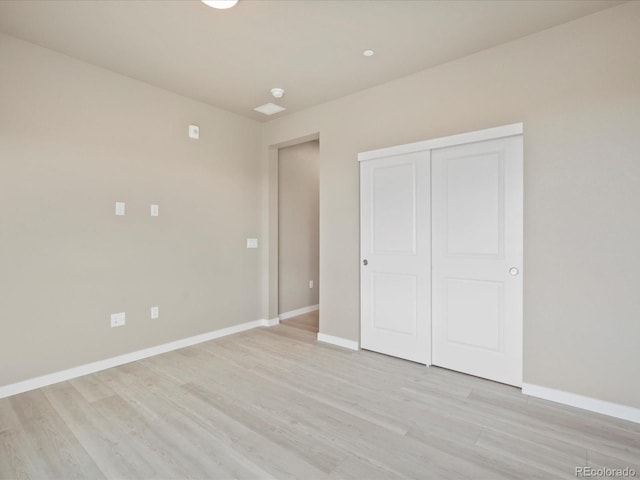 unfurnished bedroom with light wood-type flooring and a closet