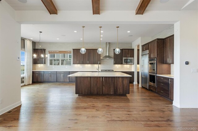 27381 E Lakeview Dr, Aurora, CO 80016 - kitchen featuring appliances with stainless steel finishes, wall chimney range hood, dark wood finished floors, light countertops, and dark brown cabinetry