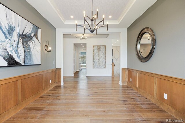 27381 E Lakeview Dr, Aurora, CO 80016 - unfurnished dining area with light wood finished floors, a raised ceiling, a chandelier, a wainscoted wall, and a decorative wall