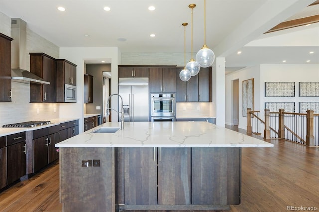 27381 E Lakeview Dr, Aurora, CO 80016 - kitchen featuring wall chimney exhaust hood, built in appliances, dark wood-type flooring, a spacious island, and backsplash
