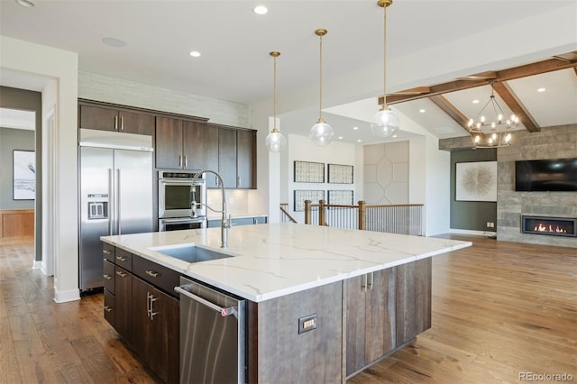 27381 E Lakeview Dr, Aurora, CO 80016 - kitchen featuring stainless steel appliances, wood finished floors, dark brown cabinets, an island with sink, and beamed ceiling