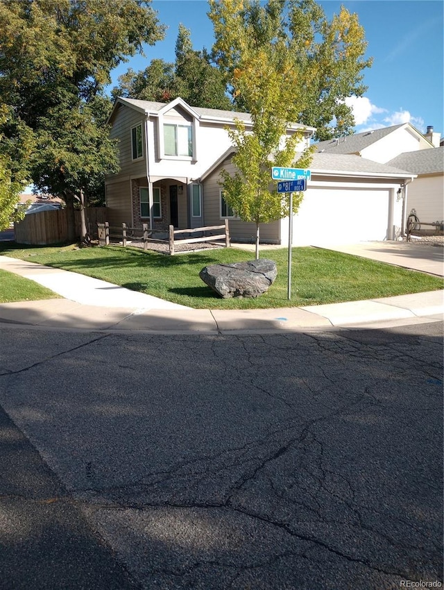 view of front of house featuring a garage, concrete driveway, a front yard, and fence