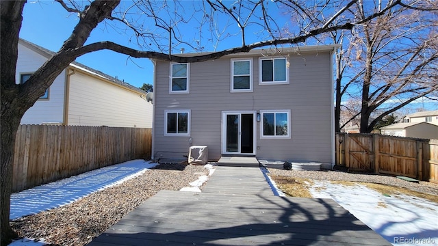 snow covered rear of property featuring a fenced backyard and a wooden deck