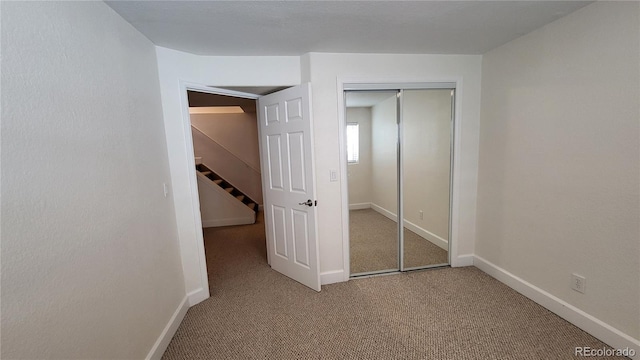 unfurnished bedroom with baseboards, a closet, and light colored carpet