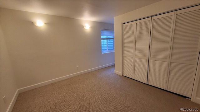 unfurnished bedroom with a closet, light colored carpet, and baseboards