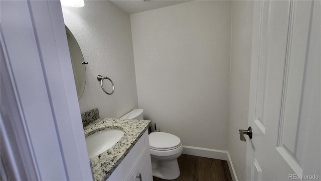 bathroom featuring toilet, baseboards, wood finished floors, and vanity