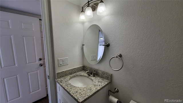 bathroom with a textured wall and vanity