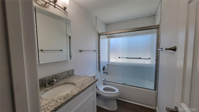 bathroom featuring combined bath / shower with glass door, vanity, and toilet