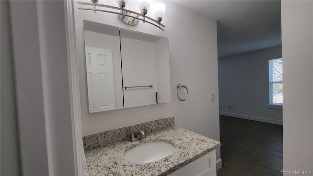 bathroom featuring a notable chandelier, wood finished floors, vanity, and baseboards