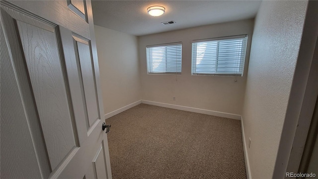 interior space featuring baseboards, visible vents, a textured wall, light colored carpet, and a textured ceiling