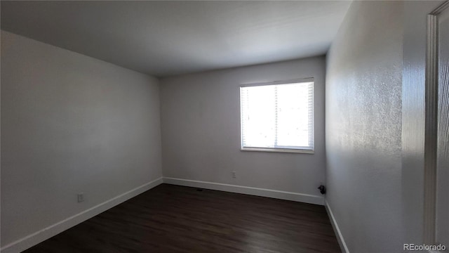 unfurnished room with dark wood-style flooring and baseboards