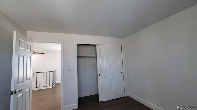 unfurnished bedroom with a closet, dark wood-style flooring, and baseboards