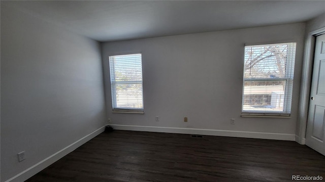 unfurnished room featuring baseboards and dark wood finished floors