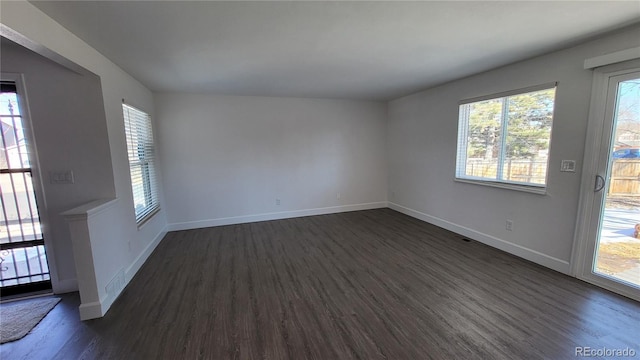 spare room featuring dark wood-style floors and baseboards