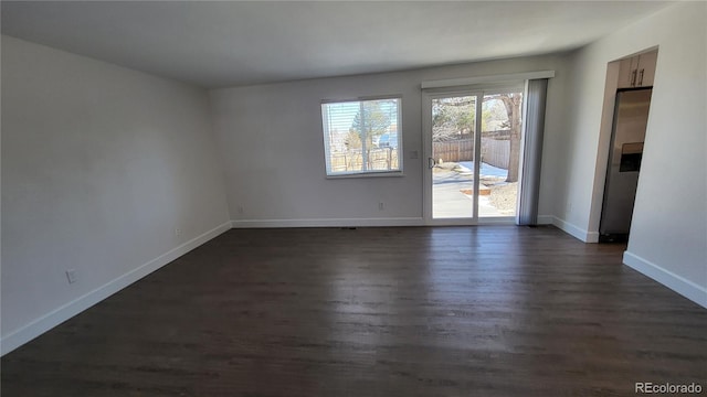 spare room with dark wood-type flooring and baseboards