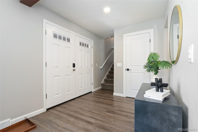 foyer with dark wood-style floors, visible vents, baseboards, and stairs