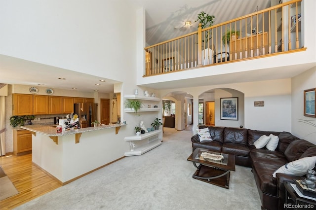 5134 S Ouray Ct, Centennial, CO 80015 - living area with arched walkways, a high ceiling, light wood-type flooring, and baseboards