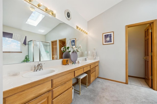 5134 S Ouray Ct, Centennial, CO 80015 - bathroom featuring vaulted ceiling, a skylight, double vanity, a shower stall, and baseboards