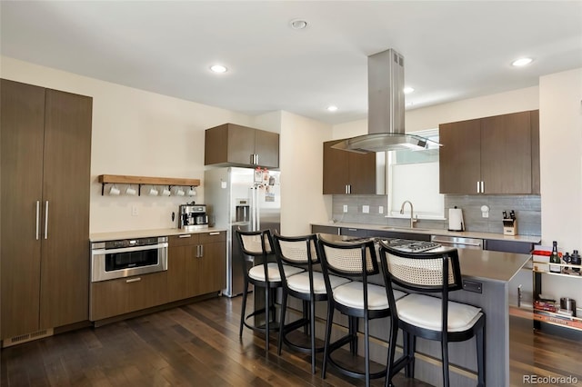 kitchen with sink, stainless steel appliances, a center island, dark hardwood / wood-style floors, and island exhaust hood