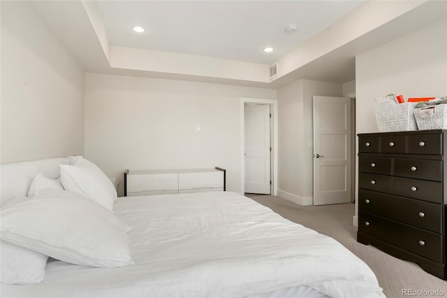 bedroom with a raised ceiling and light carpet