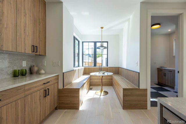 kitchen featuring breakfast area, decorative light fixtures, tasteful backsplash, and light wood-type flooring