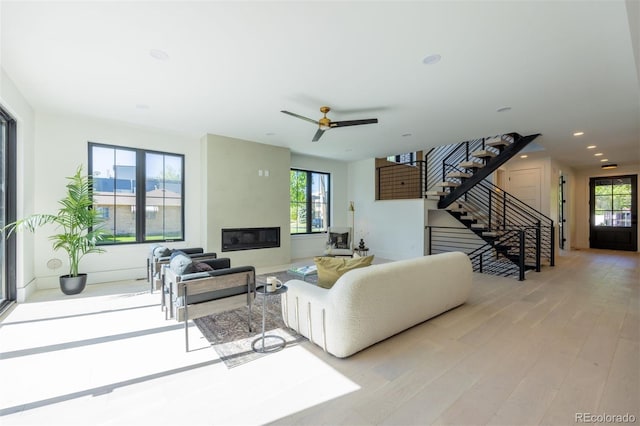 living room featuring ceiling fan, plenty of natural light, and light wood-type flooring