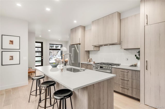 kitchen with sink, an island with sink, high quality appliances, and a kitchen bar