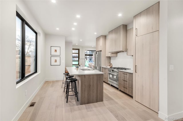 kitchen featuring a breakfast bar, sink, custom exhaust hood, a center island with sink, and high quality appliances