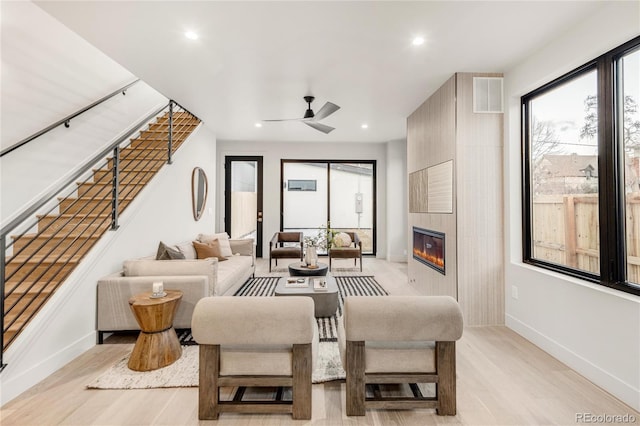 living room with light hardwood / wood-style flooring, a fireplace, and ceiling fan