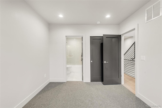 unfurnished bedroom featuring connected bathroom and light colored carpet