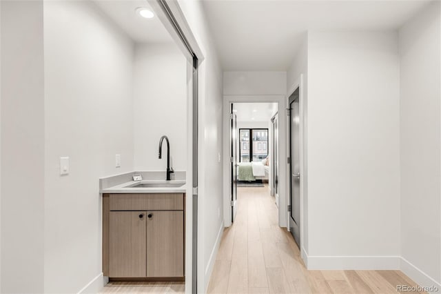 hallway with sink and light hardwood / wood-style flooring