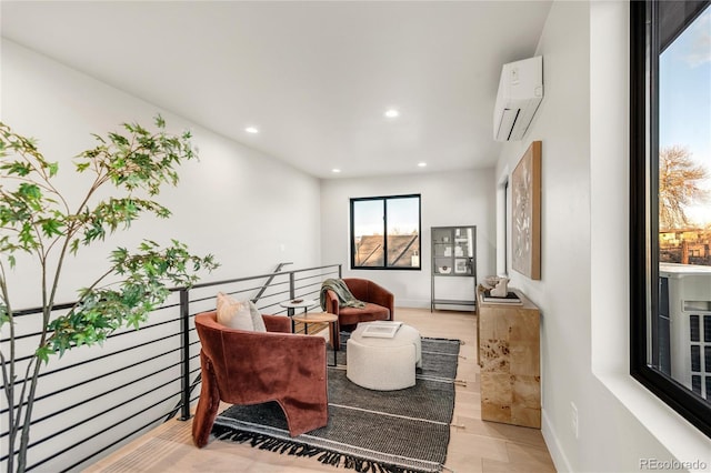 sitting room with wood-type flooring and a wall mounted air conditioner