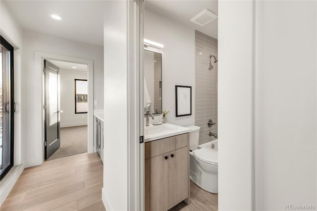 full bathroom with vanity, hardwood / wood-style floors, tiled shower / bath combo, and toilet