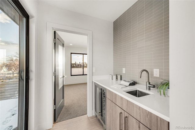 kitchen featuring sink, light colored carpet, wine cooler, and decorative backsplash