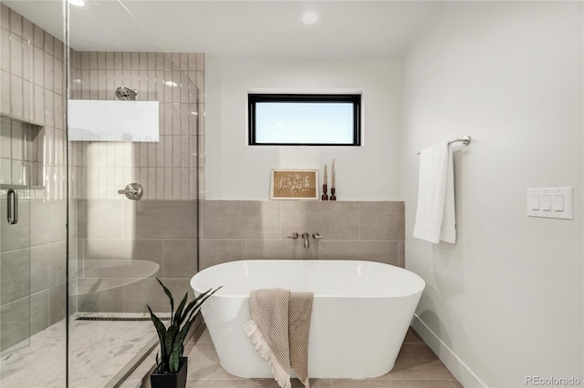 bathroom featuring independent shower and bath, tile patterned flooring, and tile walls