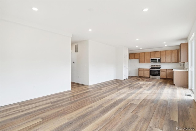 unfurnished living room with sink and light wood-type flooring