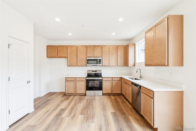 kitchen with appliances with stainless steel finishes, light hardwood / wood-style floors, sink, and light brown cabinets