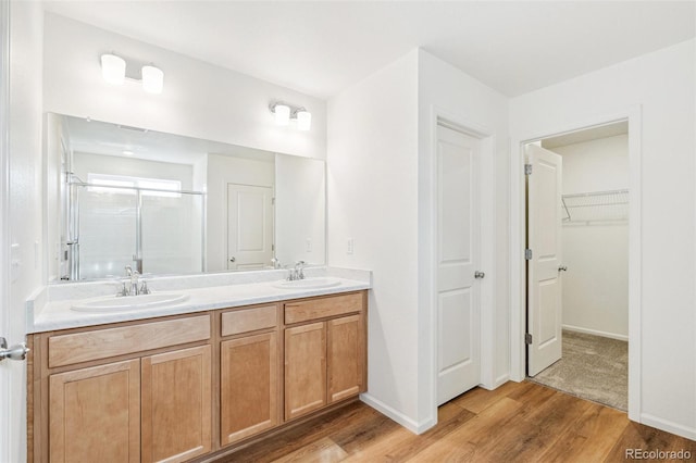 bathroom featuring an enclosed shower, vanity, and wood-type flooring