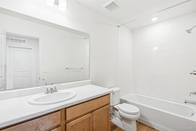 full bathroom featuring tiled shower / bath combo, vanity, hardwood / wood-style flooring, and toilet