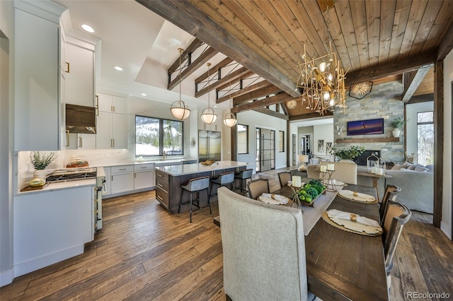 dining space with healthy amount of natural light, dark wood-style floors, beamed ceiling, a chandelier, and recessed lighting