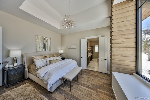 bedroom featuring dark wood-style flooring, a chandelier, and a tray ceiling